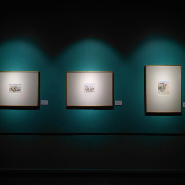 Framed artworks illuminated on a museum wall in Manila, capturing modern aesthetics.